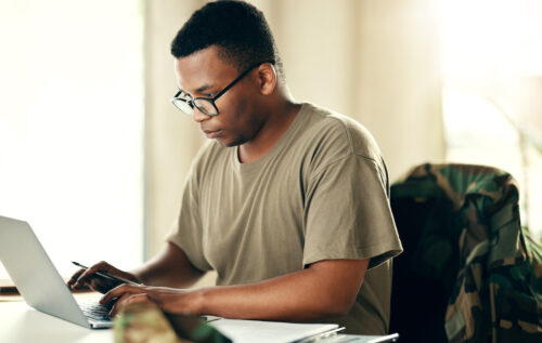 a man in a green shirt and glasses looking at a cellphone