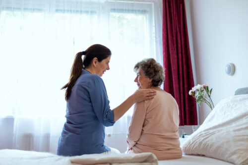 a woman sitting on a bed with a woman touching her shoulder