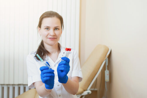 a woman in a white coat holding a syringe and a tube