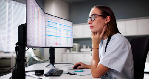 a woman sitting at a desk looking at a computer screen